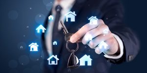 businessman holding keys with houses around